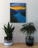 16" wide x 20" tall, original oil painting of river rushing through the mountains under a sunset sky, unframed, displayed over table