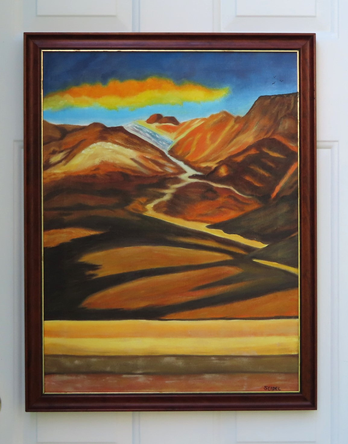 original oil painting of colorful mountains and plains with colorful clouds in sky framed in complementary wood frame