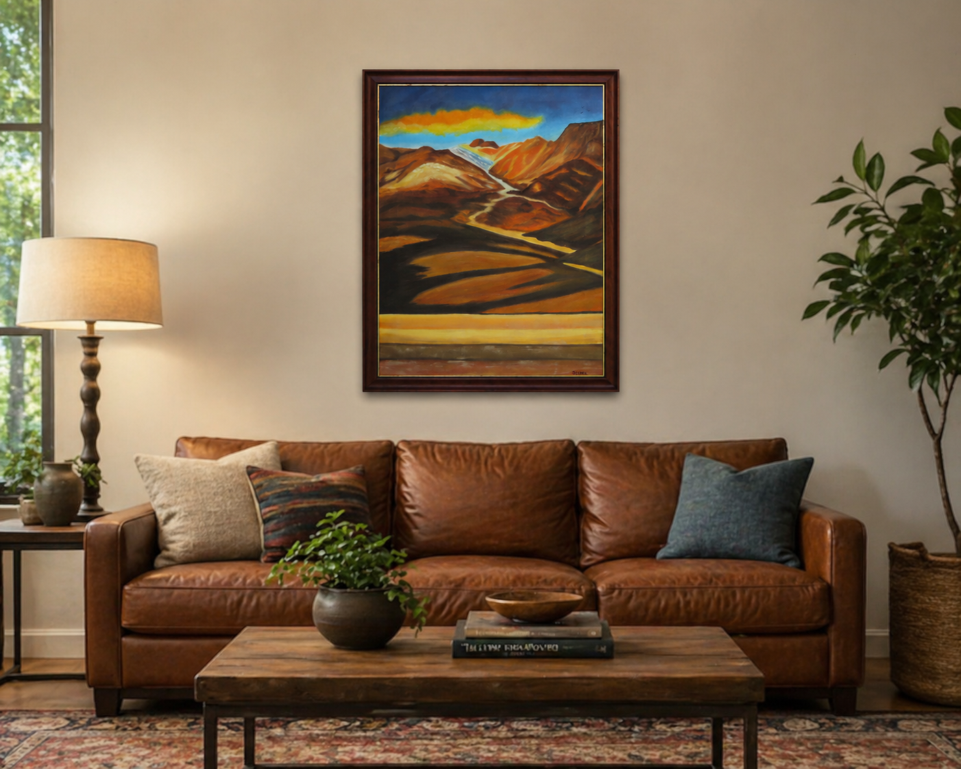 original oil painting of colorful mountains and plains with colorful clouds in sky framed in complementary wood frame, displayed over livingroom sofa