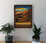 original oil painting of colorful mountains and plains with colorful clouds in sky framed in complementary wood frame, shown over table