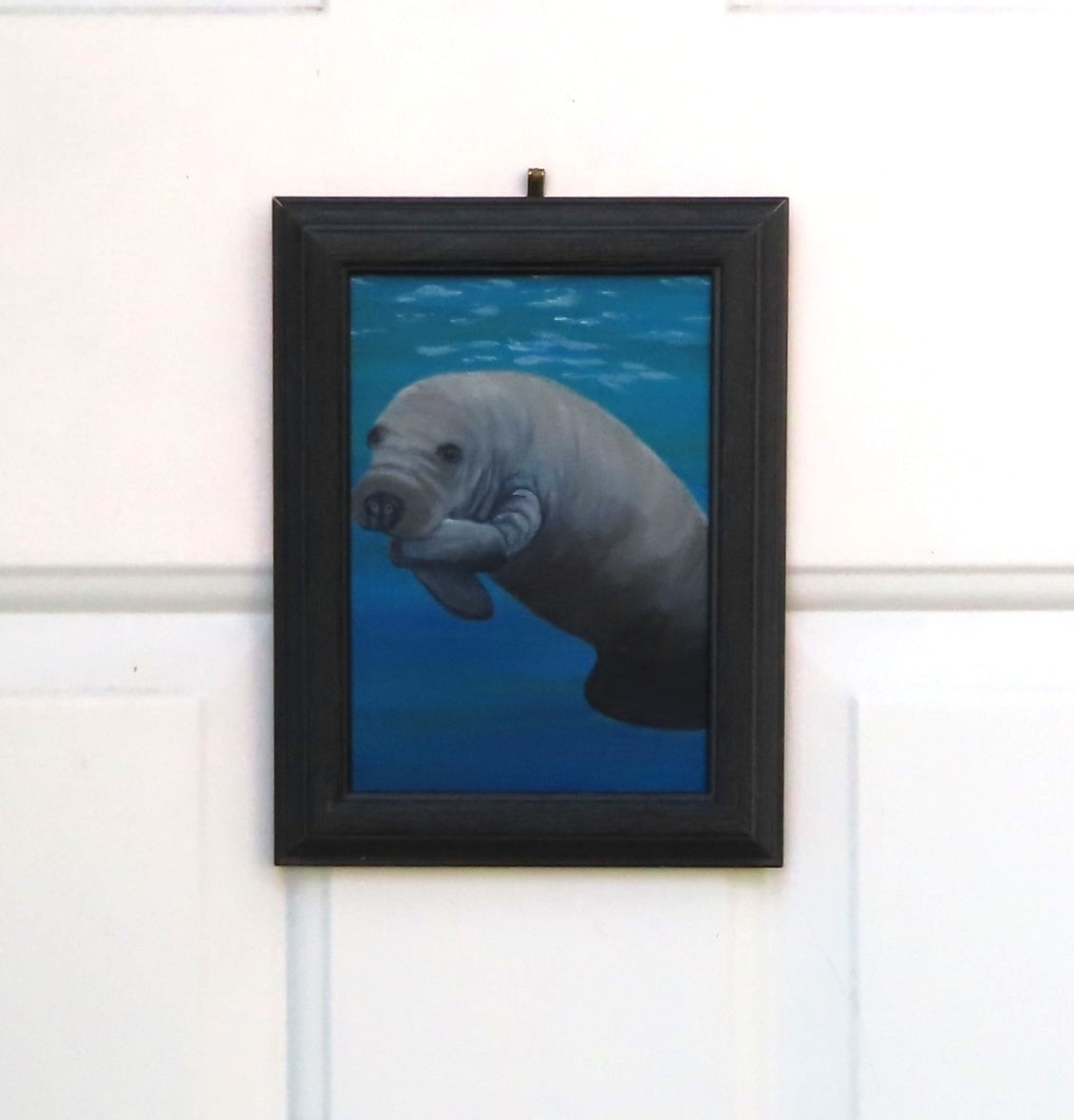 closeup painting of a baby manatee in blue waters, nicely framed