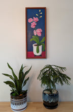 original oil painting on board of pink orchids against a royal blue background, in a white pot, framed in a handmade red chestnut colored frame, displayed over a table