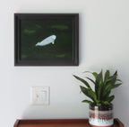 11x14" Original oil painting of a beluga whale in emerald colored ocean, framed in black, shown over a secretarydesk