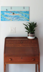 12x24" original oil painting of a swimmer performing butterfly stroke, shown over a secretary desk