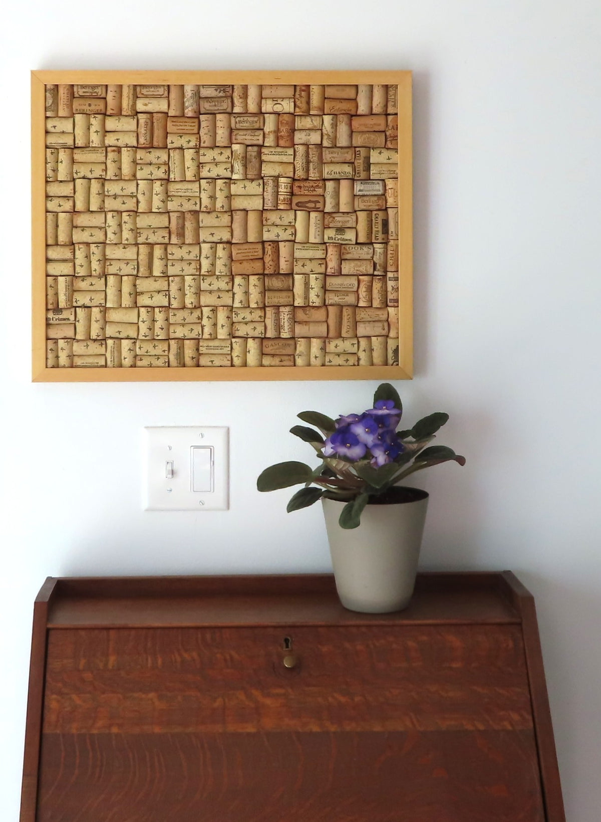 17x21" original wood framed corkboard, handmade with real wine corks, many from local Missouri wines. Blond wood, with a solid wood backboard. Sells with ideally sized pushpins. Shown over a secretary desk.