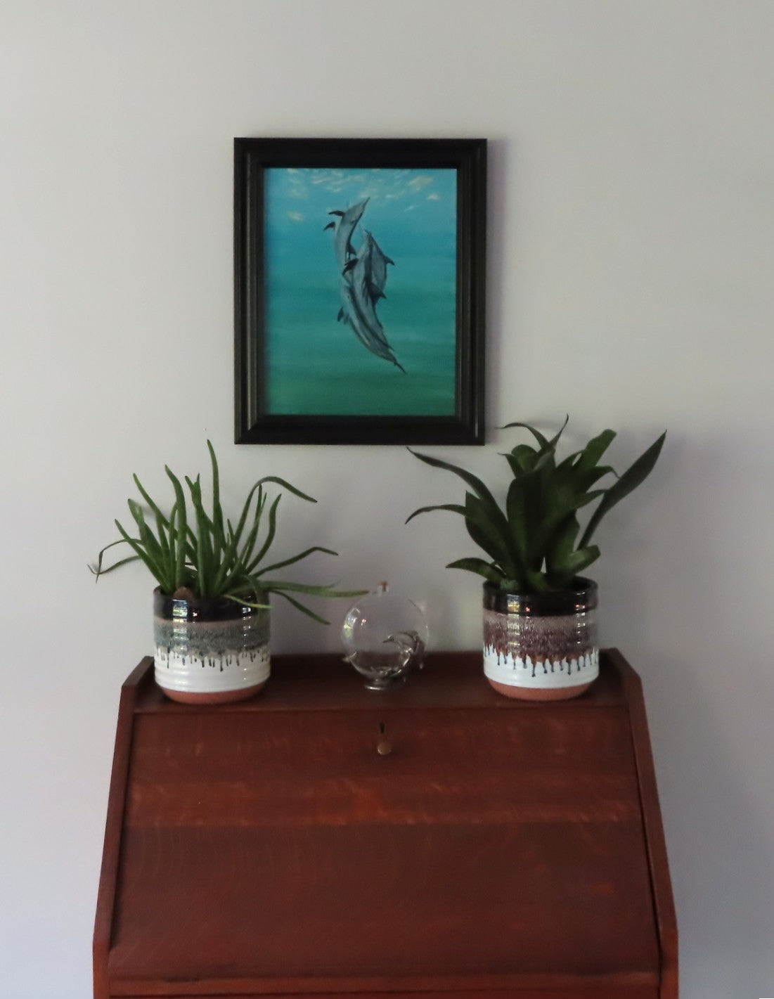 original 11x14 acrylic painting of do[hins appearing to dance in the ocean, shown here over secretary desk