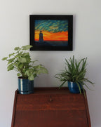 original oil painting of Erie Pierhead light house silhouetted by beautiful sunset and clouds, painted on 11 x 14 canvas panel, framed in modern black frame, displayed over secretary desk