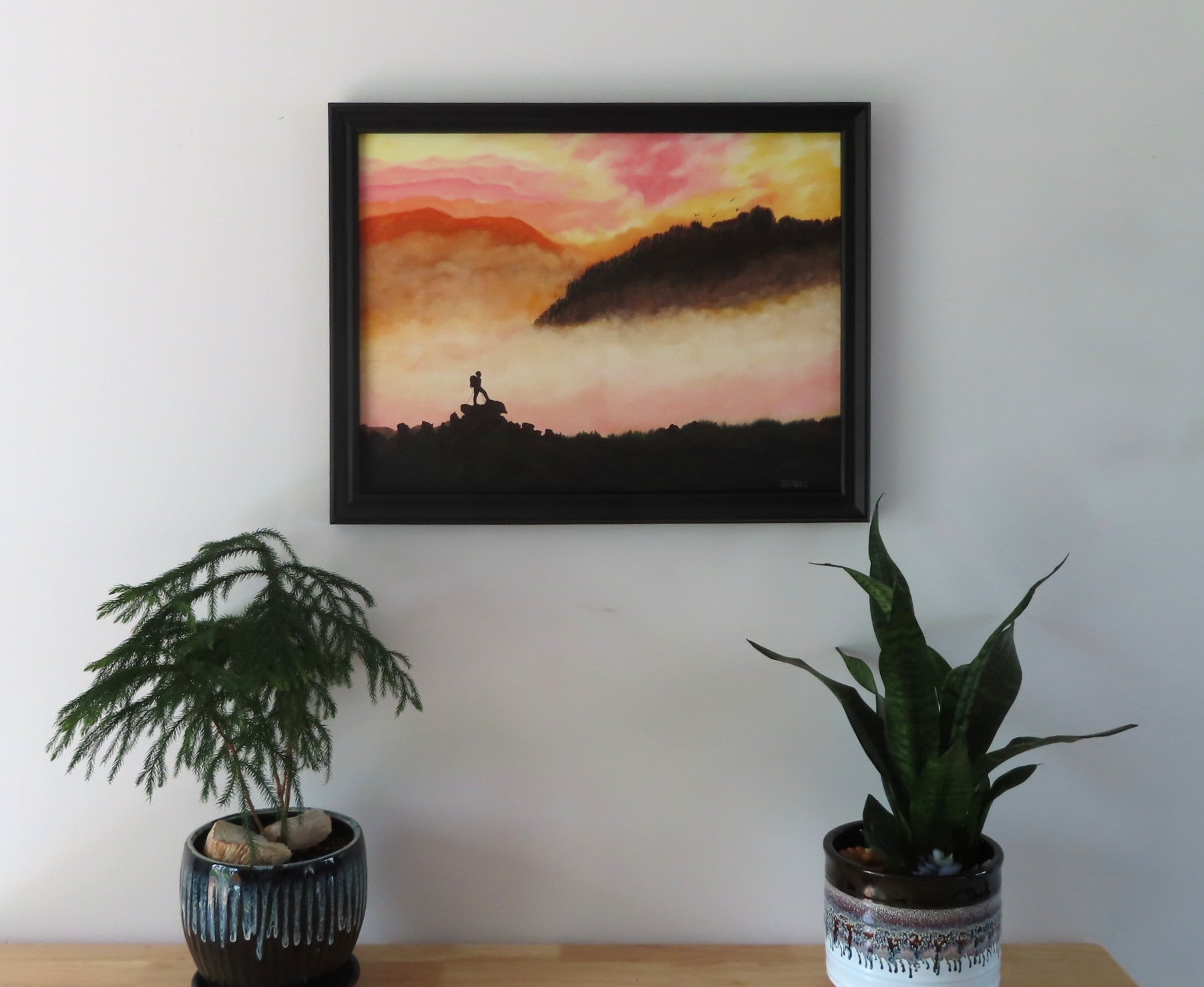 18" tall x 24" wide  original oil painting, pastel pallette, beautiful mists in mountains, climber, framed in black, displayed on wall over table