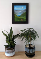 Original oil painting of a misty morning in the mountains, moon, lakes, deer in meadow, framed, shown over table