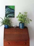 abstract poured acrylic painting on 11x14" canvas, flowing blues, greens and white create movement, one display option shown over secretary desk