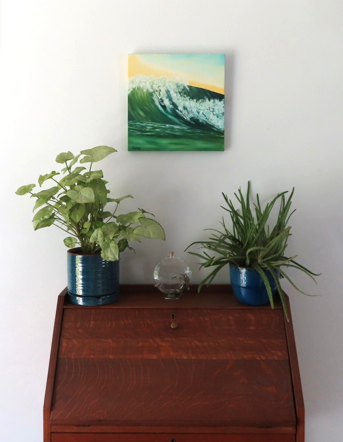 12x12" original oil painting of a surfer in the curl of a huge wave, shown here over a secretary desk