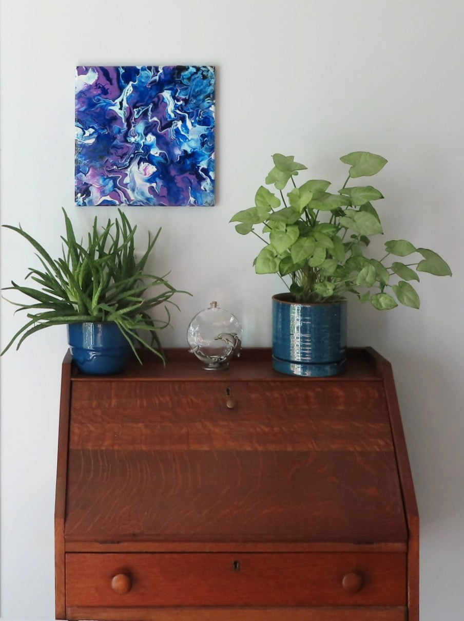 original abstract poured acrylic painting on 12x12" canvas, bright swirling purples, white and rich blues seem energetic, shown here in an alternate direction over a secretary desk