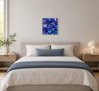 original abstract poured acrylic painting on 12x12" canvas, bright swirling purples, white and rich blues seem so  energetic that they could be moving, shown here over a bed
