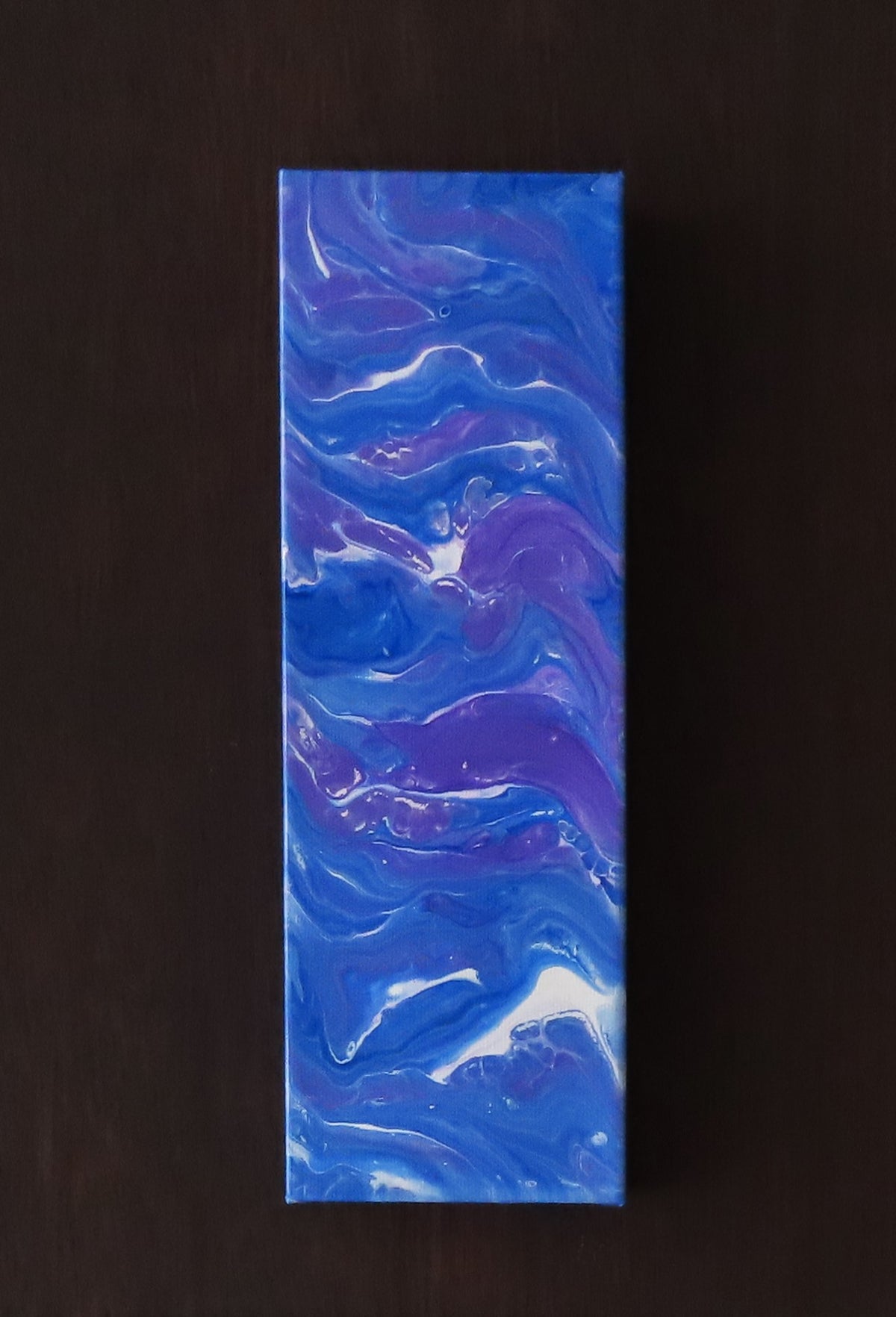 4 inches wide by 12 inches tall liquid acrylic painting with blues, purple and white, shown on a dark background. 
