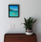 8x10" original acrylic-painting of two kayakers in a calm cove heading toward another island, beautiful turquoise water and blue sky, shown over a secretary desk