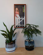 original oil painting of lady in doorway, handmade frame, pictured over table