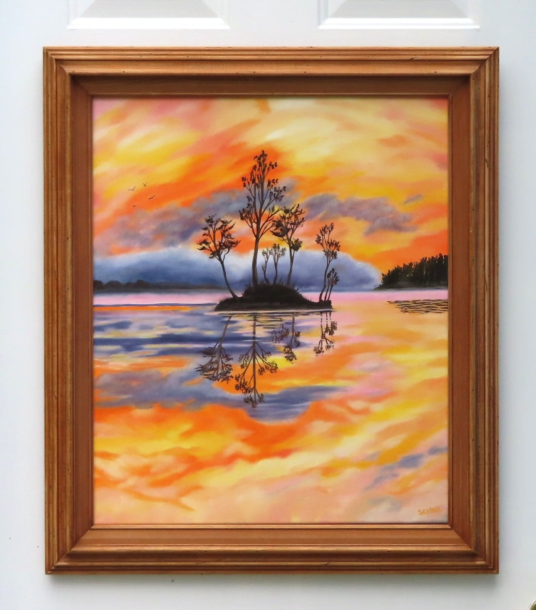 Original oil painting of a colorful pastel sky, the oranges, yellows and pinks contrast with the distant hills rising out of the mist and the dark silhouetted island and trees reflected in calm waters 24" tall by 20" wide framed with lovely red chestnut frame