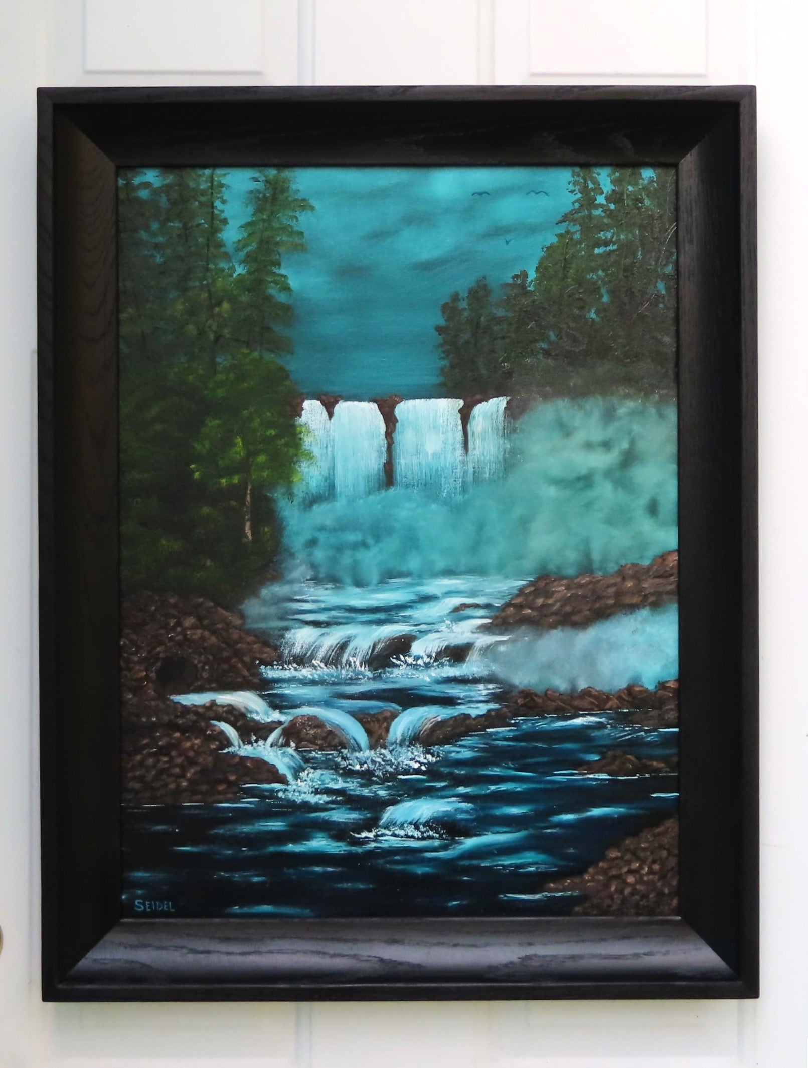 original painting of bright waterfalls and mist contrast with dark woods and rushing river, framed