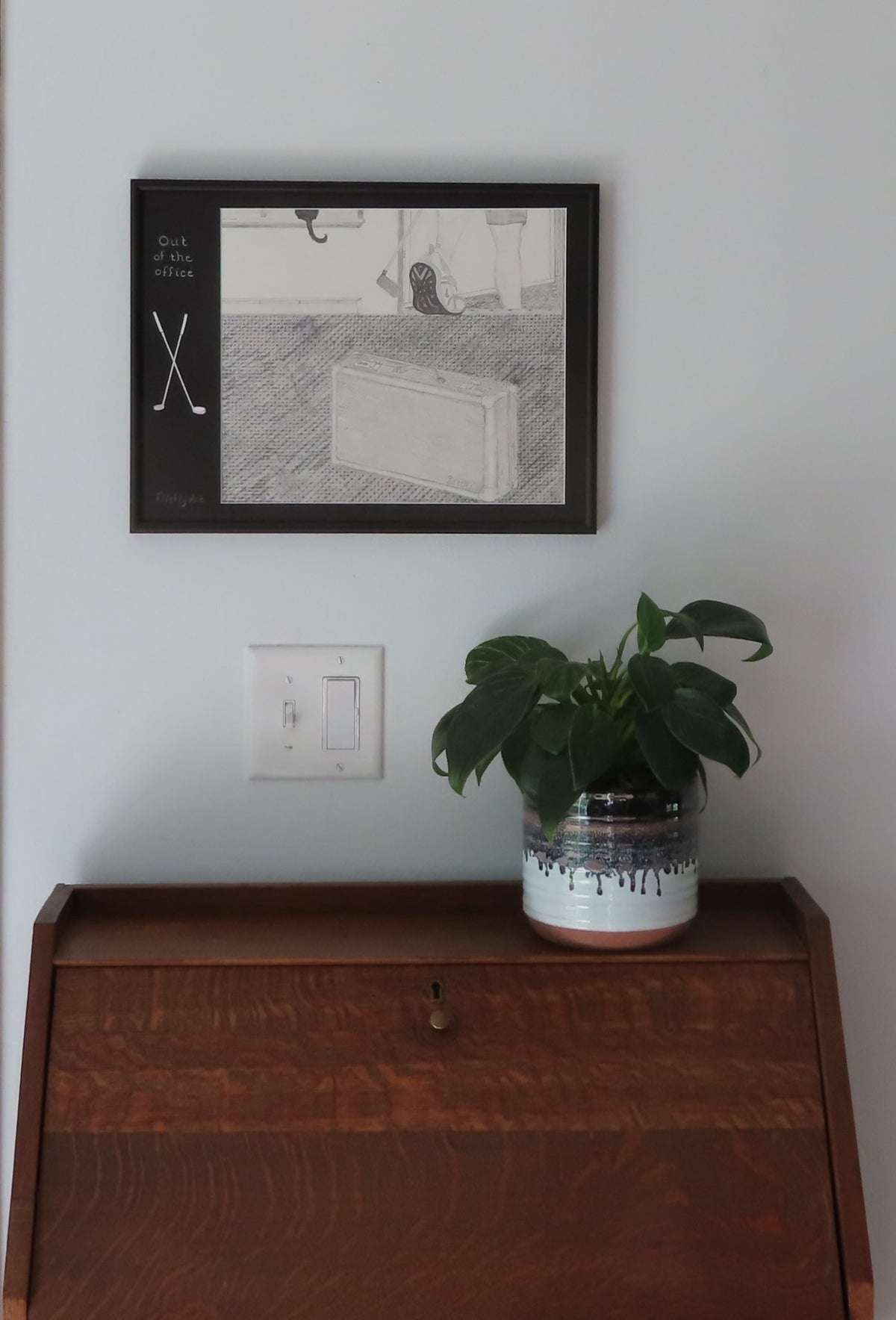 12x16"  Framed original graphite drawing of someone walking out the door with a golf club. Features a specialty mat with carved in golf clubs, shown over a secretary desk