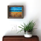 8 1/2 x 10 1/2" by 3" deep shadow box with an original acrylic painting, featuring the Atlantic ocean with sailboats. Mixed media in the foreground features sand a fence and log, shown over a secretary desk. 