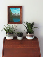Original 9x12 oil painting of lake, mountains, canoe, framed in red oak wood frame, shown over secretary desk