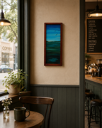 somewhat abstract view of sky, water, distant hills and birds in flight, original 10 inches by 23 1/2 inches, oil painting, repurposed hardwood frame, pictured in a cafe