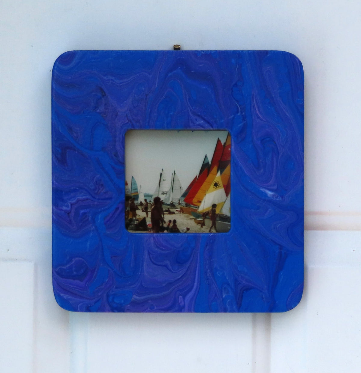 This 7 3/4"- wide by 8" tall has a 3 1/4" by 3 1/4" window for an inspirational quote or a photo of your choice. It is solid wood with an original acrylic poured painting with blues and purples. Shown here with a sample photograph option.