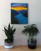 16" wide x 20" tall, original oil painting of river rushing through the mountains under a sunset sky, unframed, displayed over table