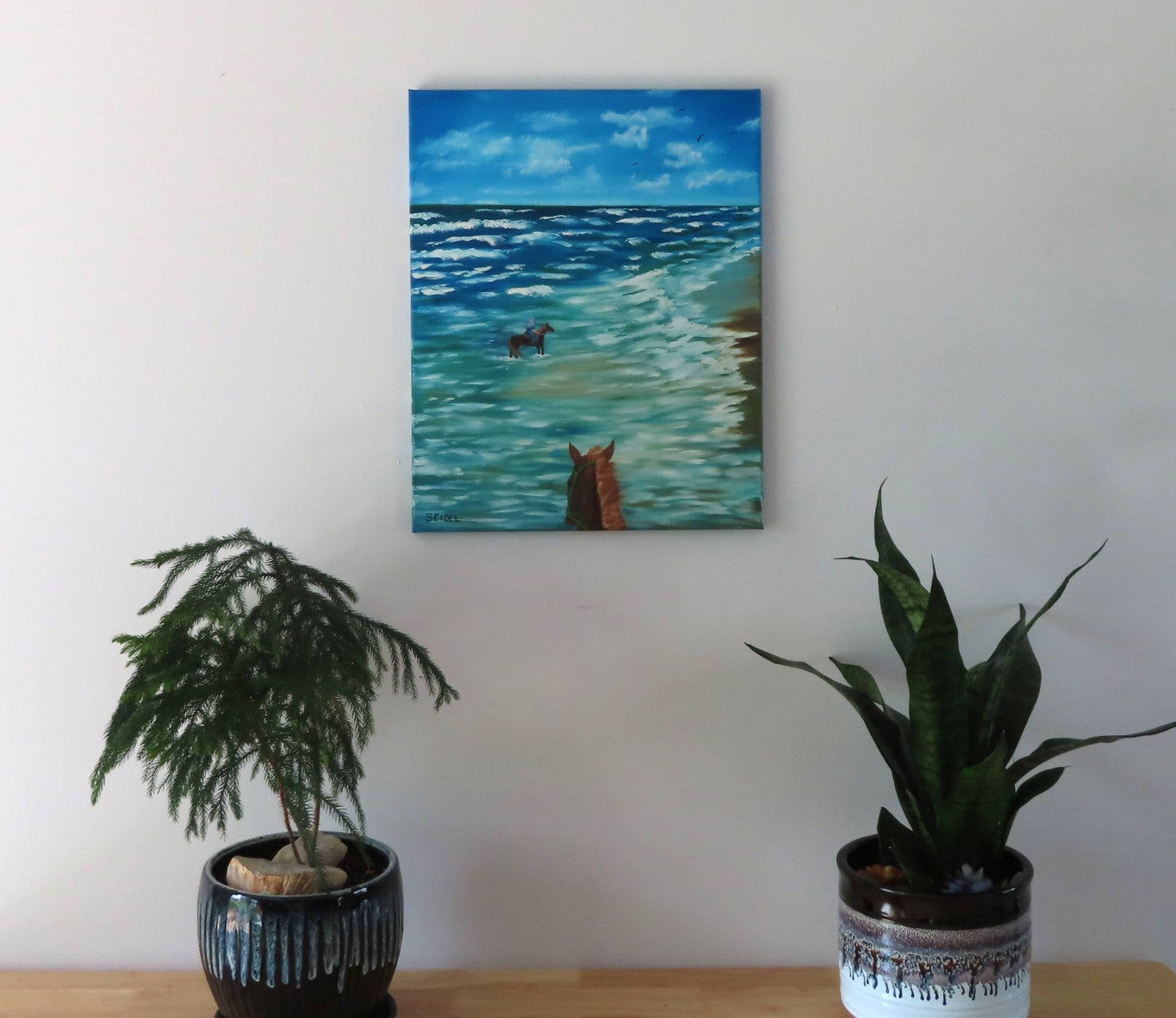16x20 original oil painting of horseback riders in the ocean, unframed, positioned on wall over table 