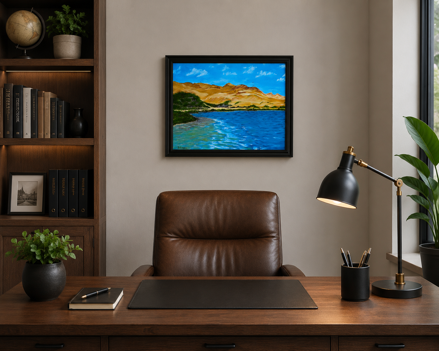 original oil painting of contrasting desert sands meeting the ocean, framed in black displayed behind desk