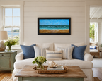 12x24 original oil painting of ocean, waves, sailboats, paragliders, and sandy beach, framed in black, pictured in a summer cottage