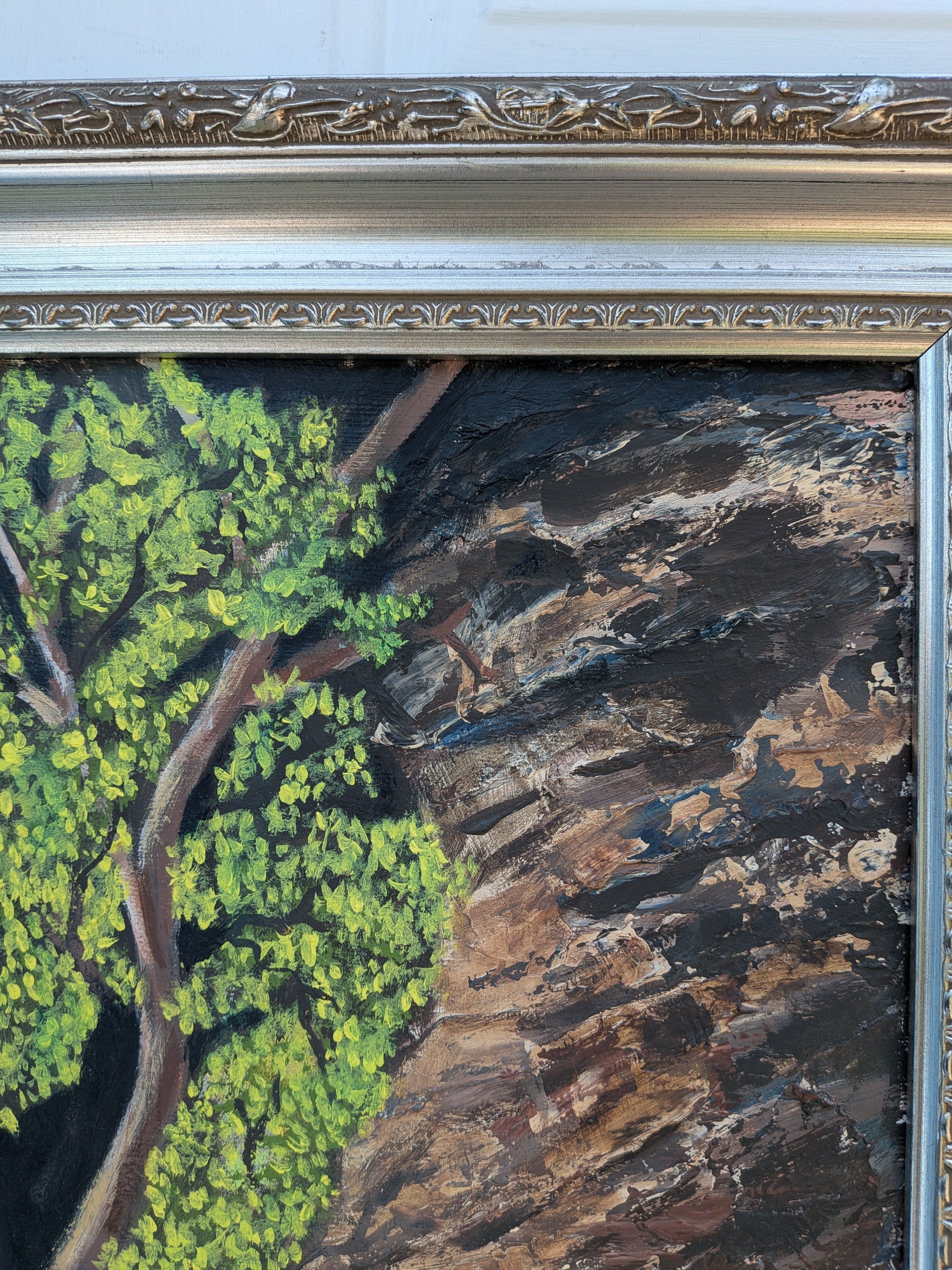 An original 16x20 oil painting on canvas featuring a lone tree with bright green leaves, illuminated by sunlight, with a dark, mysterious background and a rocky cavern, displayed in an ornate wood frame, close-up texture