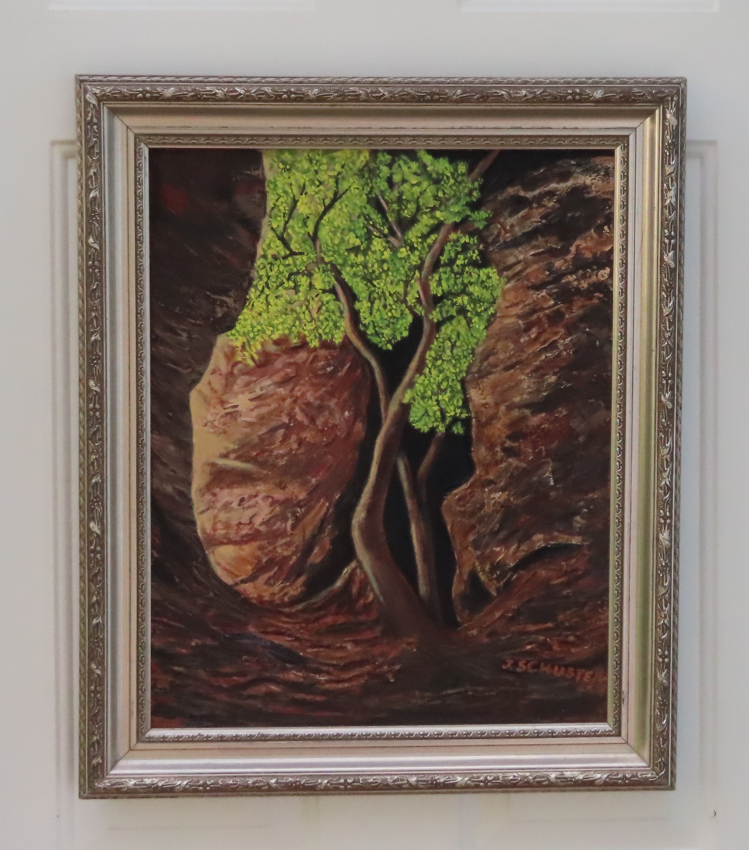 An original 16x20 oil painting on canvas featuring a lone tree with bright green leaves, illuminated by sunlight, with a dark, mysterious background and a rocky cavern, displayed in an ornate wood frame
