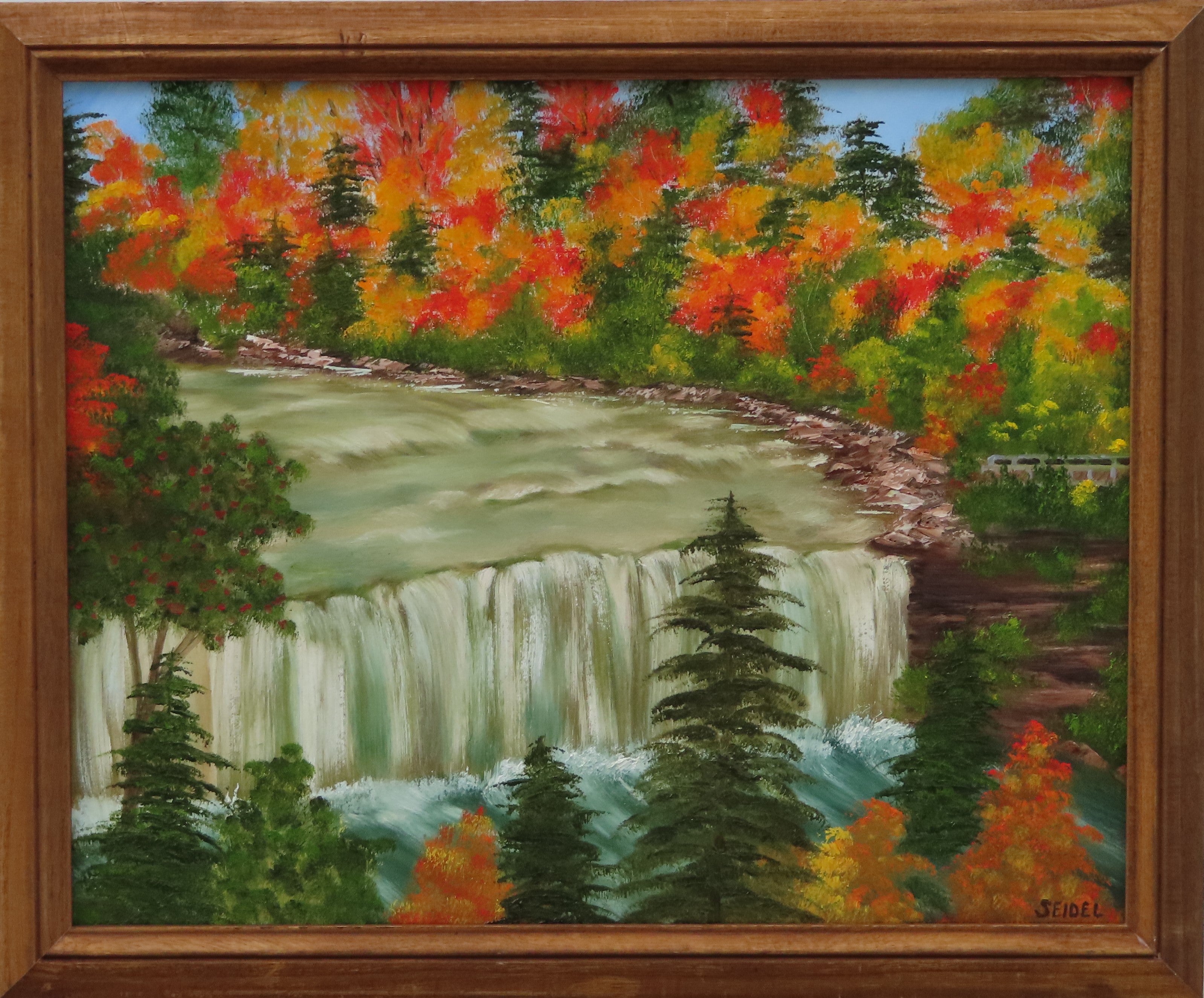 painting of bright fall colors, contrasting evergreens and waterfalls in walnut frame