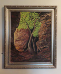 An original 16x20 oil painting on canvas featuring a lone tree with bright green leaves, illuminated by sunlight, with a dark, mysterious background and a rocky cavern, displayed in an ornate wood frame