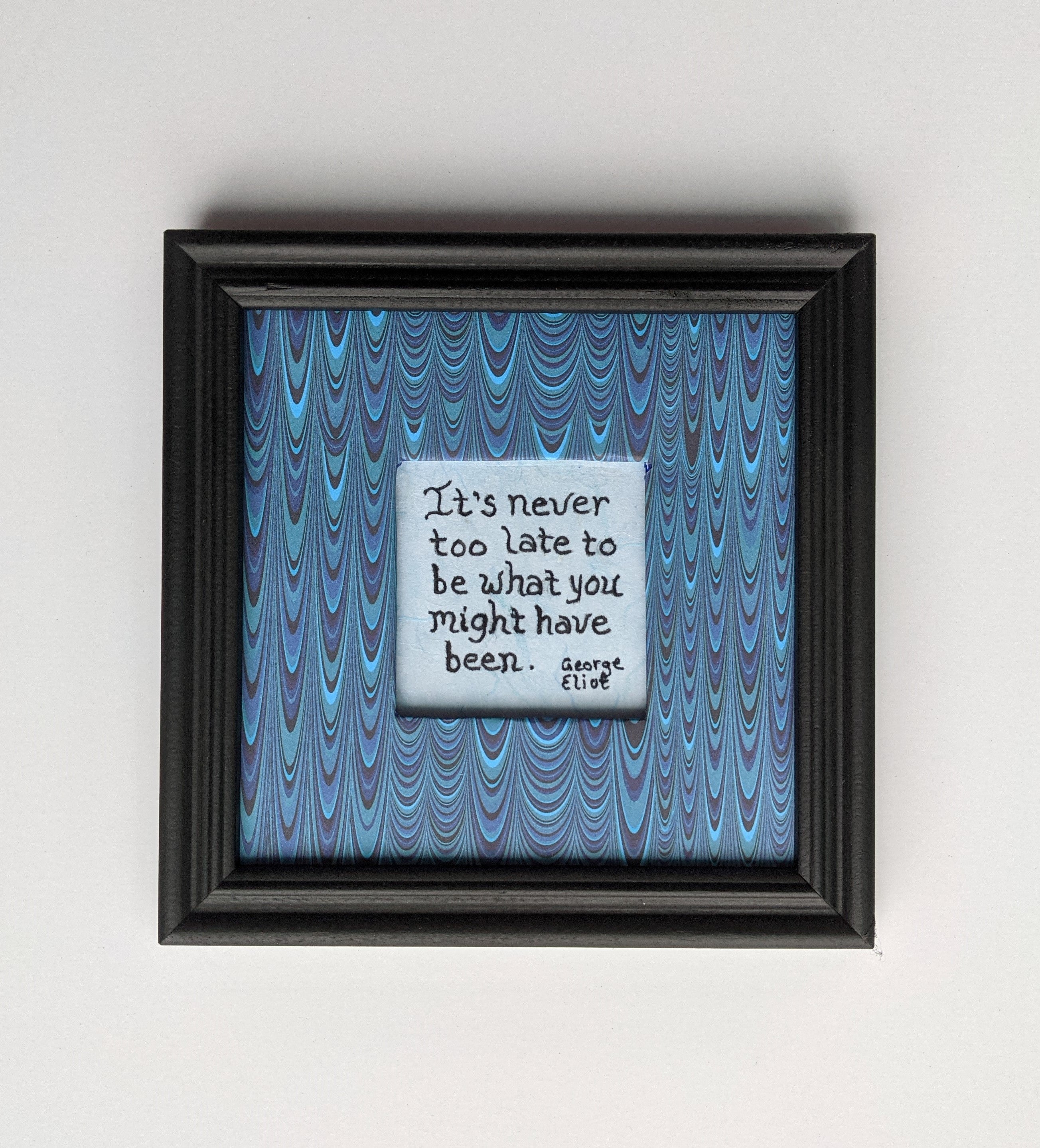 A 6x6" original framed mixed media artwork featuring an inspirational quote by George Eliot, with a blue patterned foreground and an inset light blue handmade paper with the quote
