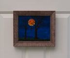 8x10" original acrylic painting, harvest moon, trees, framed, shown in dark-lit room