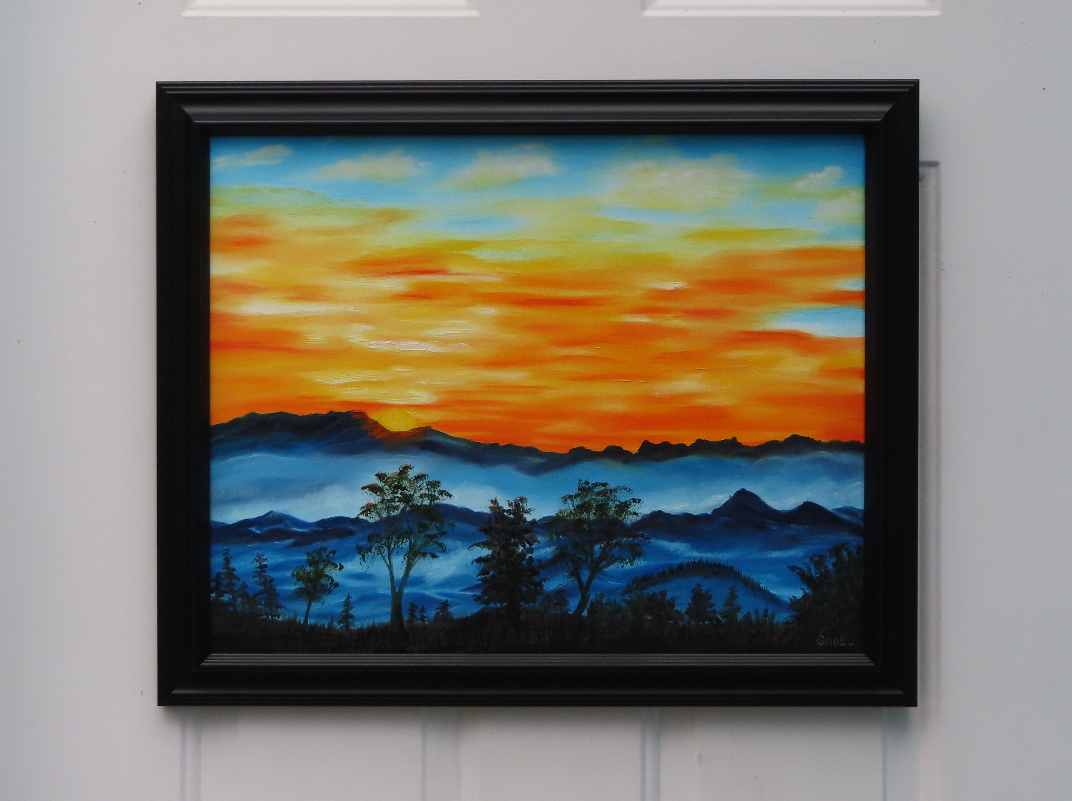 original oil painting, brilliant sunrise over misty mountains and trees, framed in black